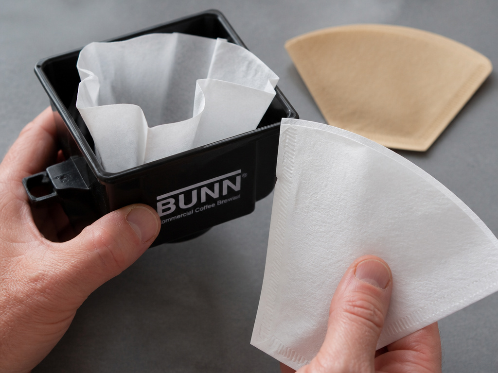 Wrong white cone filter versus correct brown basket filter for a coffee machine.
