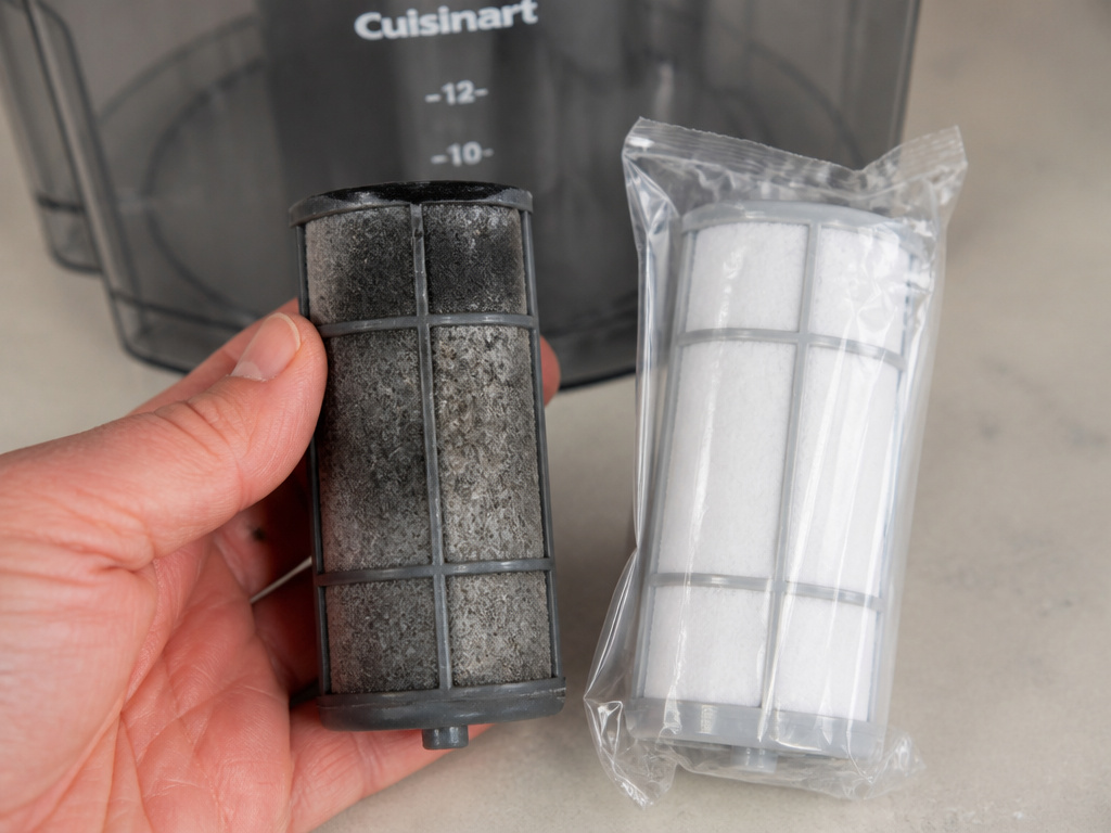 Replacing the charcoal water filter in a Cuisinart coffee maker during monthly maintenance.