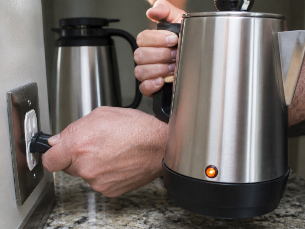 Unplugging an electric coffee percolator after brewing cycle finishes.