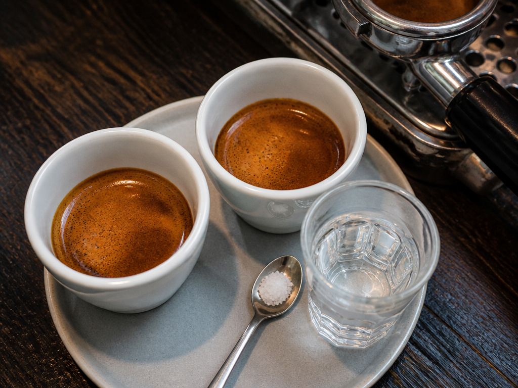 A doppio espresso served at a cafe with water and salt for tasting.